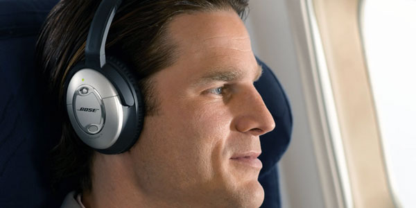 A passenger wearing Bose noise cancelling headphones in-flight.
