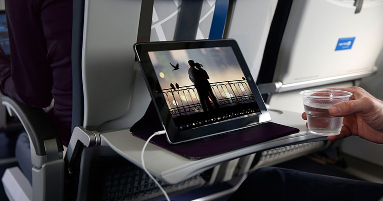 Photograph of a passenger using a tablet onboard an aircraft.